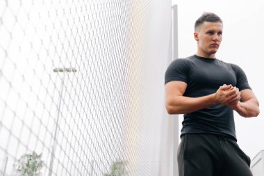 Spor fiziği olan bir adamın portresi stadyumun kapısında duruyor. Açık hava sporları konsepti.