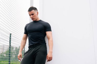Düşünceli, yakışıklı bir fitness eğitmeninin portresi. Futbol sahasındaki atletik genç adam..