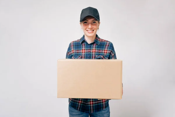 一个年轻的快递小姐手里拿着一个纸板箱 签署用纸包装运送货物的文件 — 图库照片