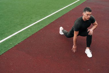 Sporcu idmandan önce ısınmak için hamleler yapar. Erkek vücut geliştirici spor sahasında eğitim görüyor. Tam stadyum planı