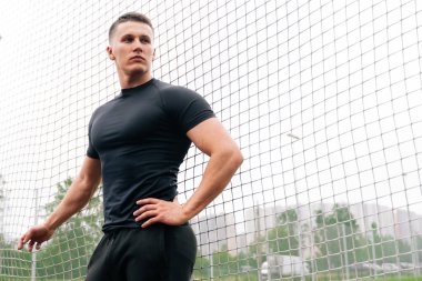 Spor giyimli genç bir adam futbol kapısının arkasında duruyor. Futbol koçu konsepti