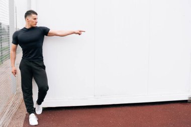 Kaslı yakışıklı bir adamın portresi, bir tarafta fitness eğitmeni. Futbol sahasındaki atletik genç adam..