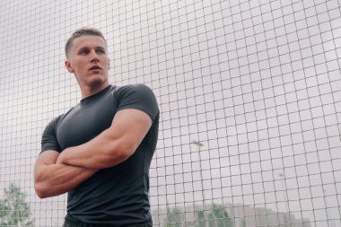 Spor fiziği olan bir adamın portresi stadyumun kapısında duruyor. Açık hava sporları konsepti.