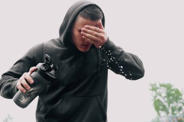 Siyah eşofmanlı bir adam karıştırıcıdan su döker. Açık hava eğitiminden sonra serinleme kavramı.