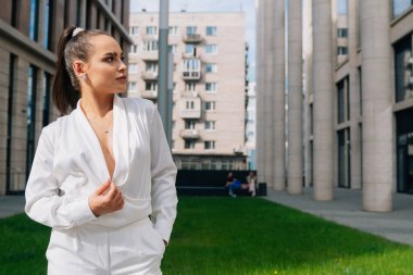 Kendine güvenen bir iş kızının portresi yana bakıyor. Beyaz pahalı takım elbiseli bir iş kadını..