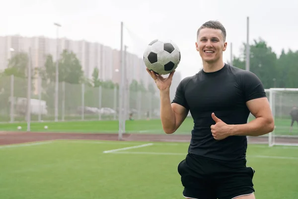 Portrait of a handsome young man with a smile holding a soccer ball. The concept of advertising a football club. Coach joyful