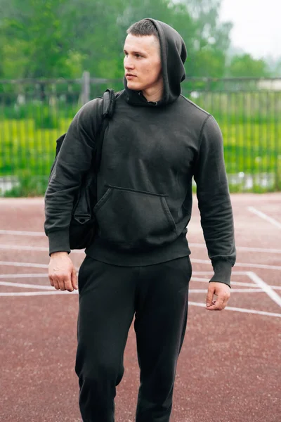 若い男が強さの訓練のためのスポーツの地面に彼の手の中に袋で歩いているフィットネストレーナー パンデミックの間の単一の訓練の概念 — ストック写真