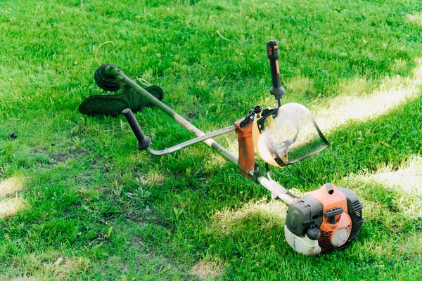 芝刈り機は夏の日に蒸気室の緑の芝生の上に立つ 背の高い草をきれいにするというコンセプト — ストック写真