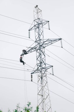 Erkek elektrikçiler elektrik kulesinde tamirat yapıyor. Elektrik hattı gökyüzüne karşı. Elektrikçi çalışma konsepti