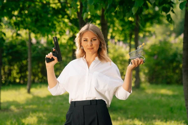 Portrait of a stylish woman holding a purse and a weapon, the concept of a failed purchase . Robbery at a time of crisis.