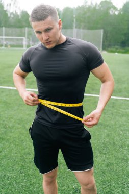 Sporcu belini bir santimetre kurdeleyle ölçer. Kasları geliştirmek için kilo alma kavramı. Zayıflama