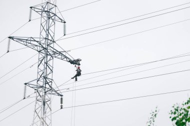 Erkek elektrikçiler elektrik kulesinde tamirat yapıyor. Gökyüzüne karşı elektrik hattı. 6 Haziran 2020 Saint-Petersburg, Rusya