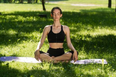 Açık hava spor giyimli bir kız kilo vermek için egzersiz yapıyor. Yoga, kavramsal işlevsel eğitim günbatımında halı kullanmak.