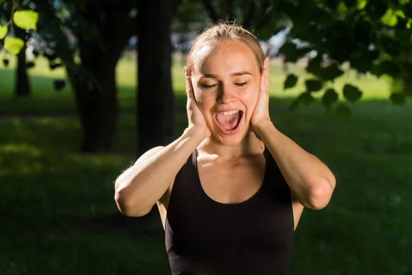 The face of a young sports girl closeup with her mouth open. The concept of shout outdoors