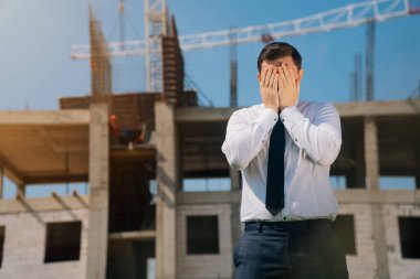 Adam elini avucunun içine almış, şaşırmış apartman uzmanı inşaat konsepti, şok mühendisi.