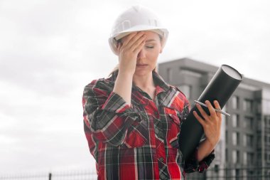 Elinde kağıt çizimleri olan düşünceli bir kadın müteahhit..