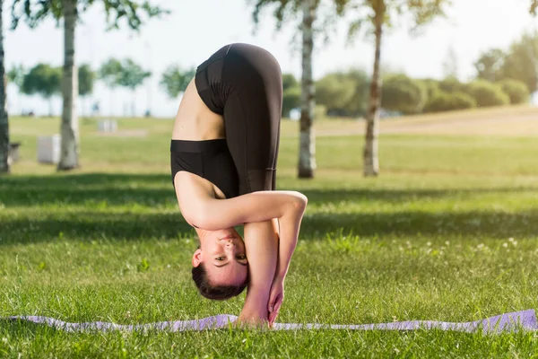 A girl in outdoor sportswear does an exercise for weight loss. Yoga, concept functional training using a rug at sunset.