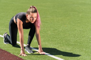 Beyaz tenli sporcu kız yarışa başlamadan önce, spor koçu koşuya hazırlanıyor, stadyumda bir yaz günü koşuya hazırlanıyor.