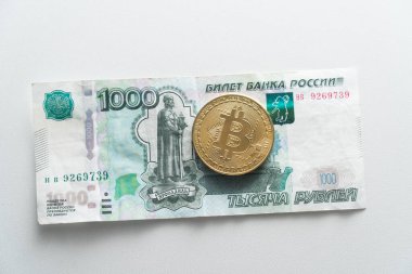 Sikke Biktcoin Rus rublesinin kağıt banknotunda yatıyor. Nakit karşılığında sanal para kavramı