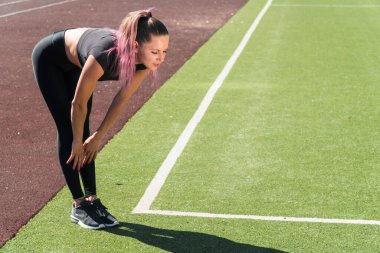 Genç bir kız atletik kız, yamaçlarını öne doğru çevirir. Stadyumdaki spor salonunda.