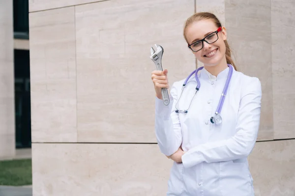 Neşeli Bir Doktor Kadın Elinde Ngiliz Anahtarı Tutuyor Tıp Kıyafetleri — Stok fotoğraf