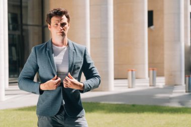 Şık bir genç adam şehrin arka planına karşı dijital bir tablet tutuyor. İnşaat mühendisi kavramının yanında çok katlı bir bina inşaatı ile ilgili belgeler bulunmakta.