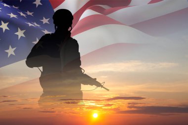 Gün batımına karşı Amerikan bayrağı taşıyan bir askerin silueti. Anma Günü, Gaziler Günü