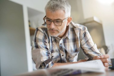 Orta yaşlı adam mutfakta gazete okuma