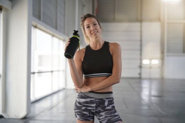 Atletik kadın fitness salonu su şişesi ile ayakta