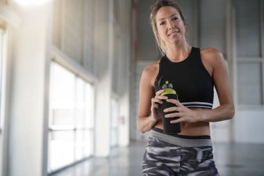 Atletik kadın fitness salonu su şişesi ile ayakta
