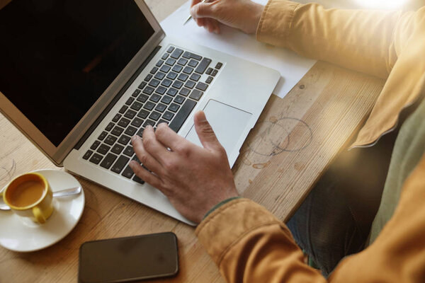 Upper view of man working on laptop at coffee shop