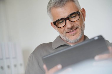 Tablet ile bağlı gülümseyen orta yaşlı adam