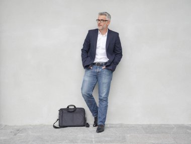 Tam uzunlukta beton duvara yaslanmış işadamı