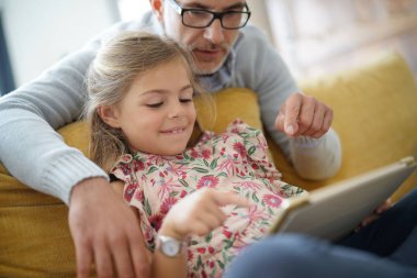 Baba ve kız kanepede oturan tablet ile bağlı