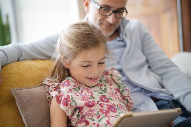 Baba ve kız kanepede oturan tablet ile bağlı