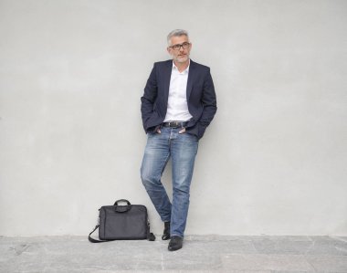 Tam uzunlukta beton duvara yaslanmış işadamı