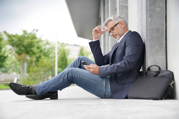 Geschäftsmann Sitzt Auf Gehweg Und Nutzt Smartphone — Stockfoto