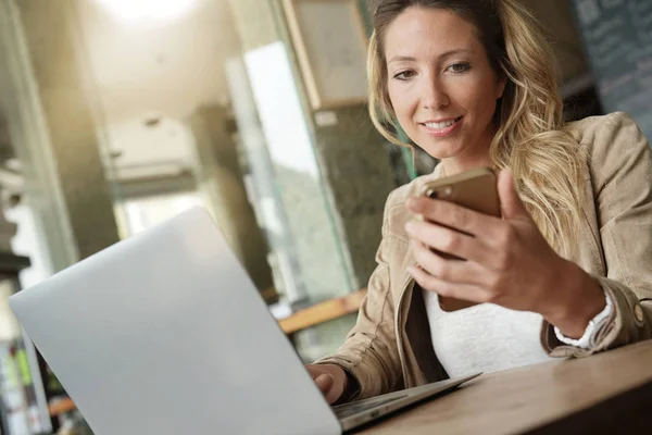 Kobieta Pomocą Smartfonu Przed Laptop Siedząc Coffeeshop — Zdjęcie stockowe