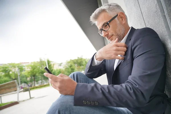 Geschäftsmann Sitzt Auf Gehweg Und Nutzt Smartphone — Stockfoto