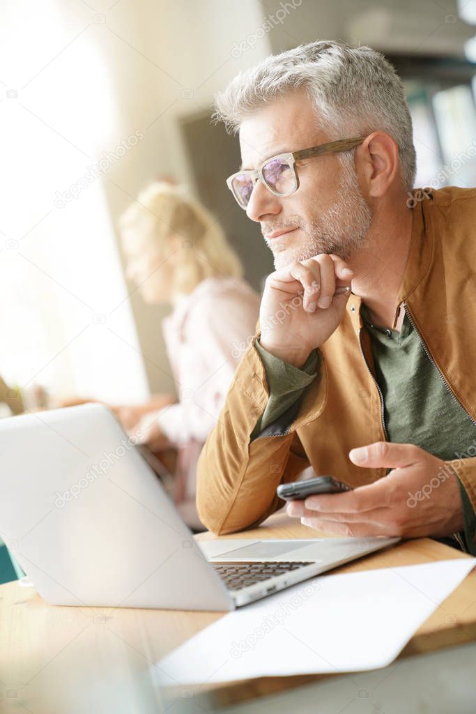 Man in trendy coffee shop looking through window