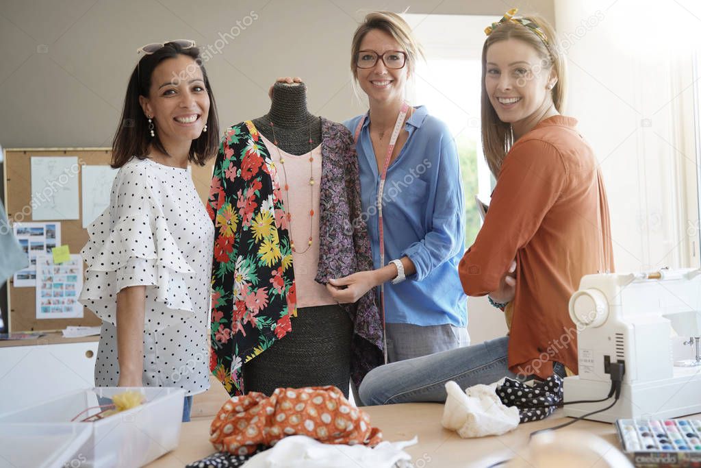 Portrait of smiling fashion designers in workshop