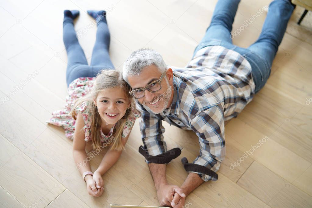 Upper view of little girl with daddy laying on wooden floor