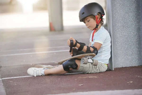 地面に座っているスケート ボードの少年 — ストック写真