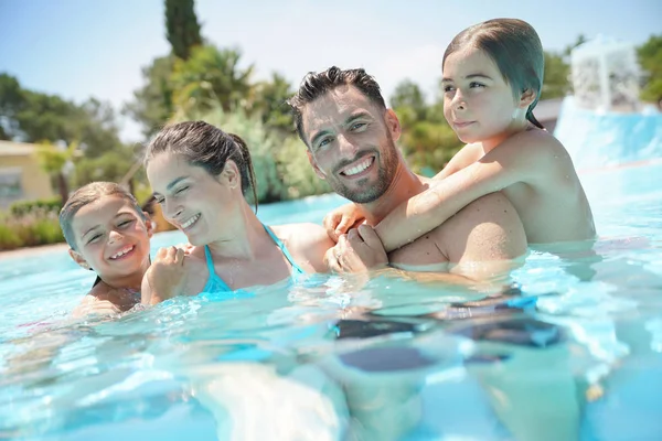 Portrait of happy family at the swimming-pool in summer