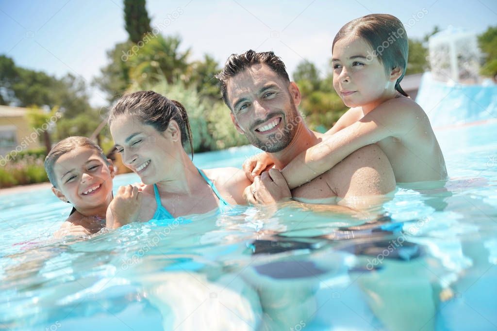 Portrait of happy family at the swimming-pool in summer 