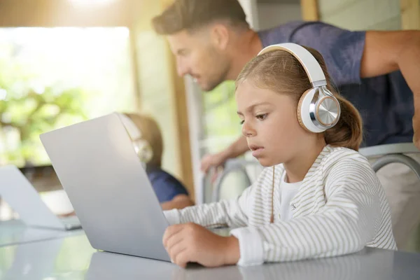 笔记本电脑屏幕前戴耳机的小女孩 — 图库照片