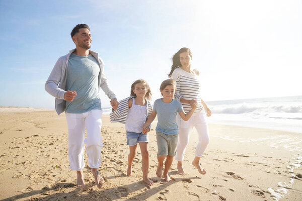 Family running on sandy beach at sunset