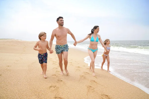 欢快的家庭在沙滩上奔跑 — 图库照片