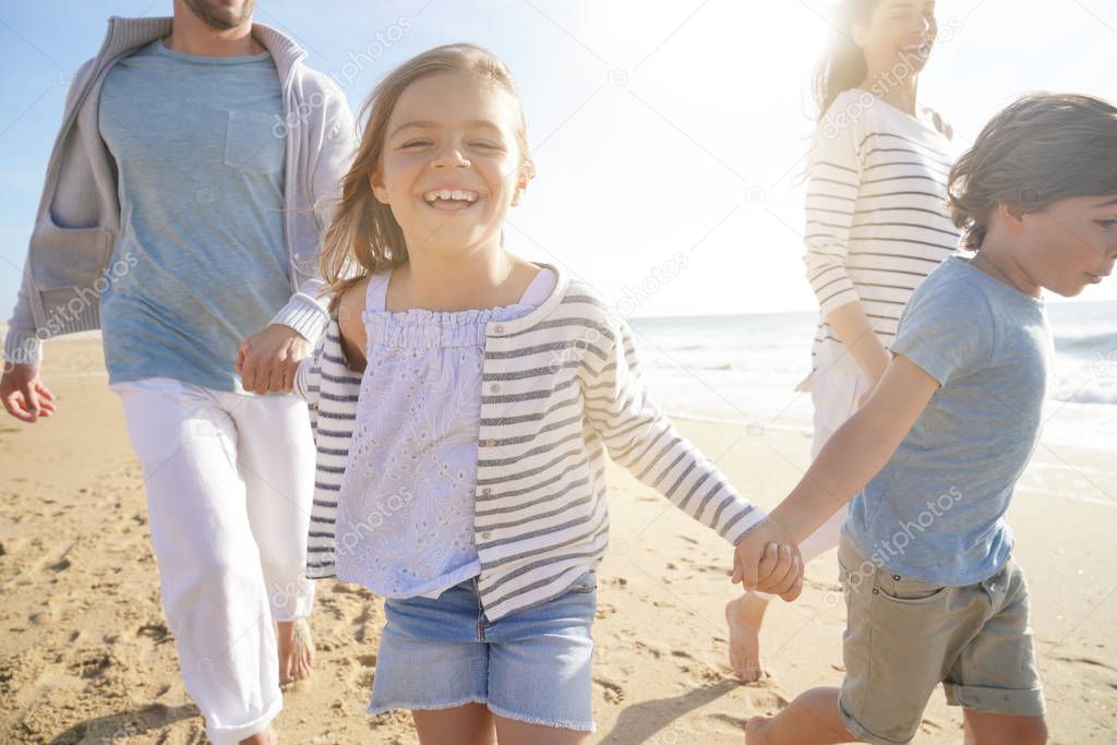 Family running on sandy beach at sunset