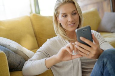 Neşeli kadın evde smartphone kullanarak